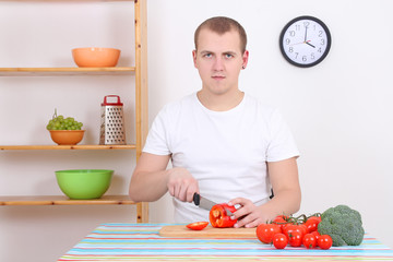 man cutting red pepper in the kitchen