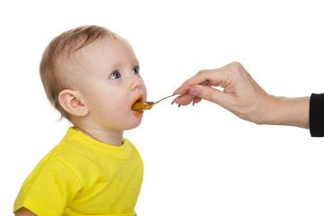 Little girl eating baby food with spoon. isolated on white