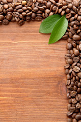 Coffee beans with leaves on wooden background