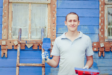 Male painter paints blue wooden wall 