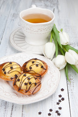 Sweet cake with cup of tea and flowers on white wooden table