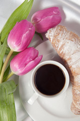 Breakfast with coffee and croissant, tulips on white silk