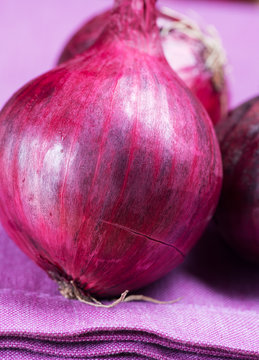 Close Up Red Onions On Purple Table Cloth