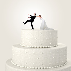 White wedding cake topper, groom tries to run away from the wedding