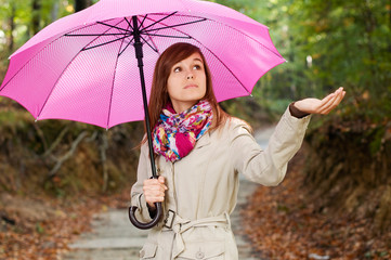 Beautiful girl with umbrella checking for rain