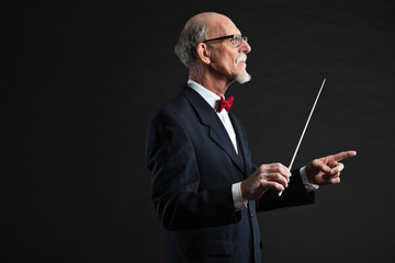 Senior conductor wearing suit. Studio shot.