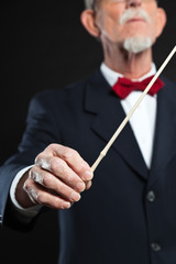 Senior conductor wearing suit. Studio shot.