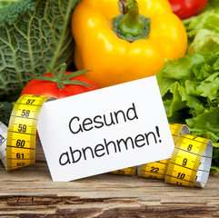 Gemüse auf Holz mit Zettel und Massband GESUND ABNEHMEN