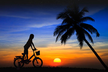 Fototapeta premium Silhouette daughter riding a bicycle on the sunset