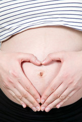 Heart made with hands on pregnant woman belly