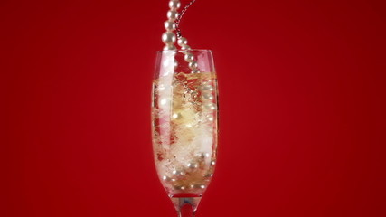 Pearl necklace falling into champagne flute - Powered by Adobe