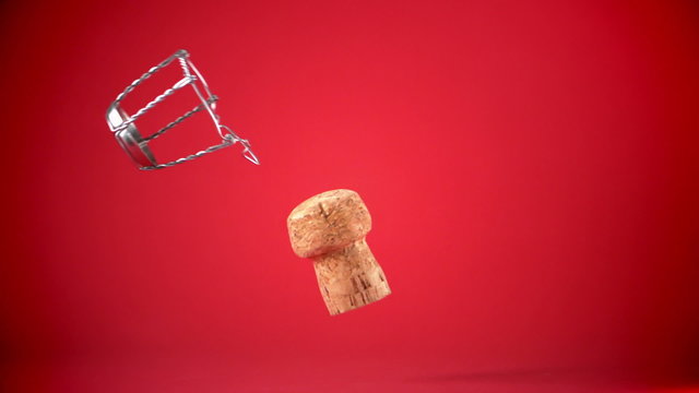 Champagne cork dropping and seperating on red background