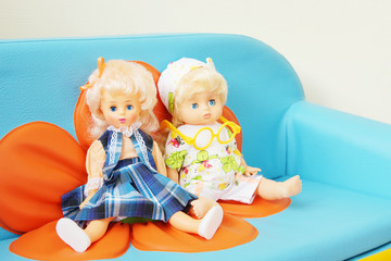 Two dolls sit on a children sofa