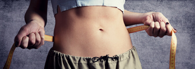 Beautiful and strong women's abs with metre. Studio shot.