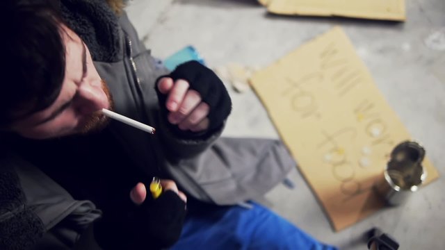 homeless man lighting a cigarette