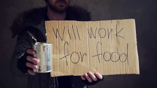 homeless hold out a tin and a cardboard with a sign