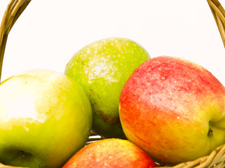 Green and red apples in a basket isolated on white background