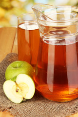 Full glass and jug of apple juice and apples