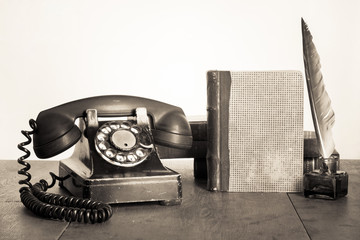 Vintage phone, old book, quill and inkwell on wooden table