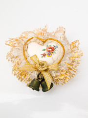 A ceramic heart decorated with bells and lace isolated on white