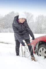 Smiling cute girl playing with tyre chains on snowy winter day