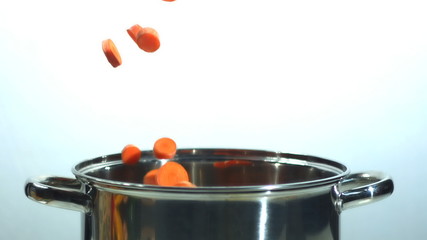 Chopped carrots falling into pot on white background - Powered by Adobe