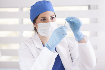 Cute female dentist checking her instruments