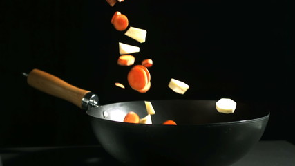 Chopped carrots and parsnips falling into a wok - Powered by Adobe