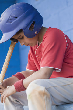 Dejected young baseball player sitting 