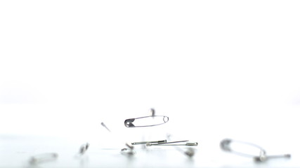 Safety pins falling on white background - Powered by Adobe