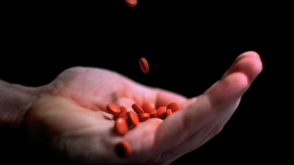 Red pills falling into hand - Powered by Adobe