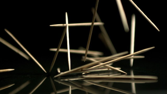 Toothpicks falling on black background