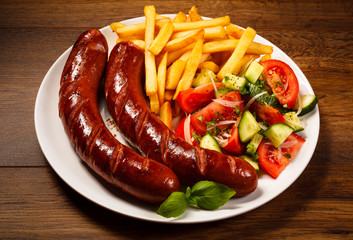 Grilled sausages, French fries and vegetables