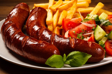 Grilled sausages, French fries and vegetables