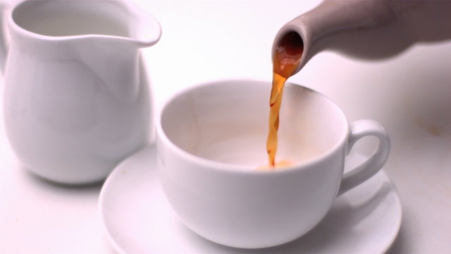 Teapot pouring tea into a cup