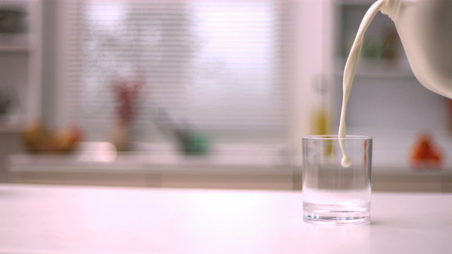 Milk pouring from plastic bottle to glass