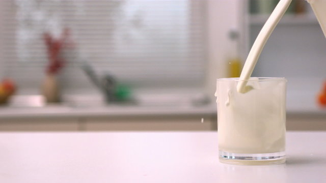Glass being filled with milk in kitchen