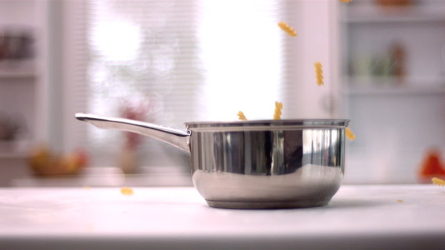 Fusilli falling in pot in kitchen