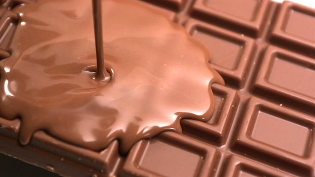 Melted chocolate being poured over a bar of chocolate