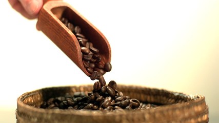 Coffee beans pouring from wooden scooper in slow motion - Powered by Adobe