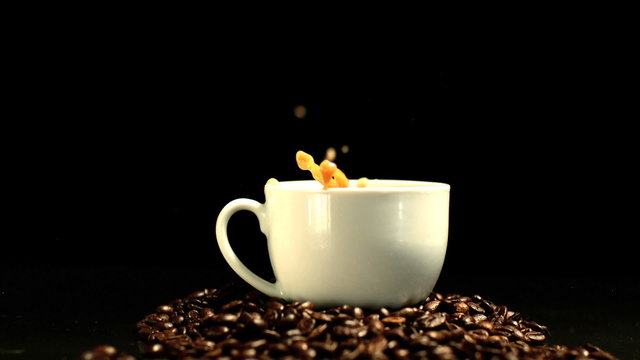 Sugar cube falling in coffee cup in slow motion