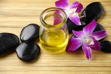 bottle of aromatherapy oil and orchid with black stones