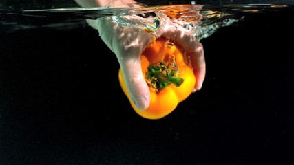 Hand taking yellow pepper from water in slow motion - Powered by Adobe
