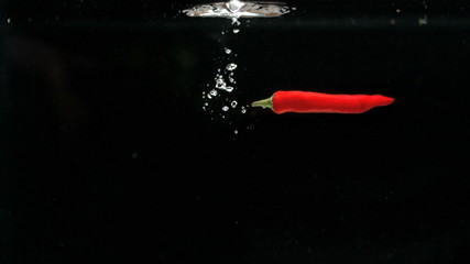 Red chili falling in water in slow motion - Powered by Adobe