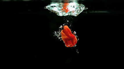 Scotch bonnet pepper dropping into water in slow motion - Powered by Adobe