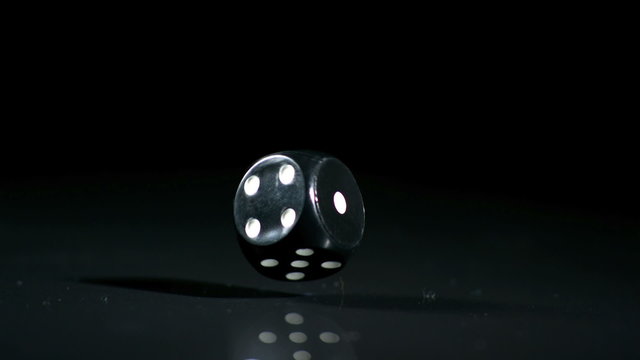 Black single die falling and bouncing close up in slow motion