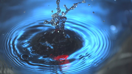Red cylinder falling into water in slow motion - Powered by Adobe