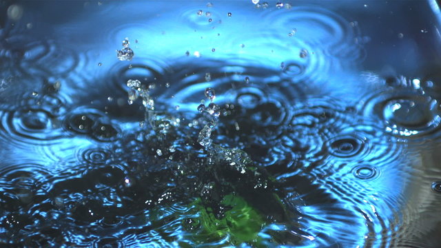 Green capsicum falling into water in slow motion