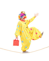 Full length portrait of a clown holding a bag and walking on a r