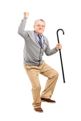 Happy senior man holding a cane and gesturing happiness